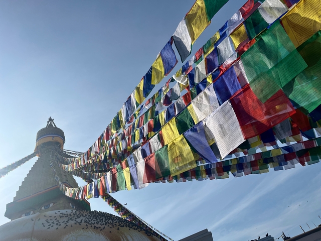 Prayer flags against the blue sky extending from a stupa.
