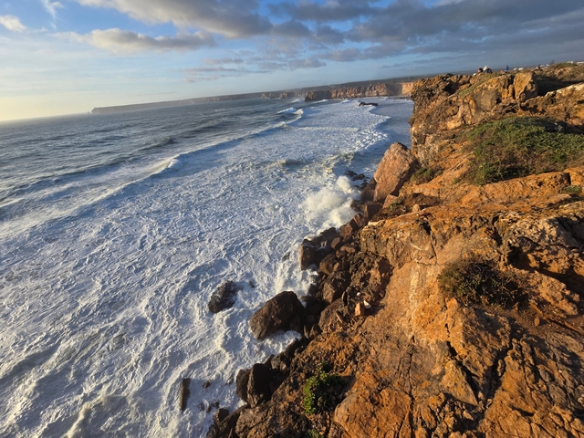 Rocky coastline with waves crashing against cliffs.