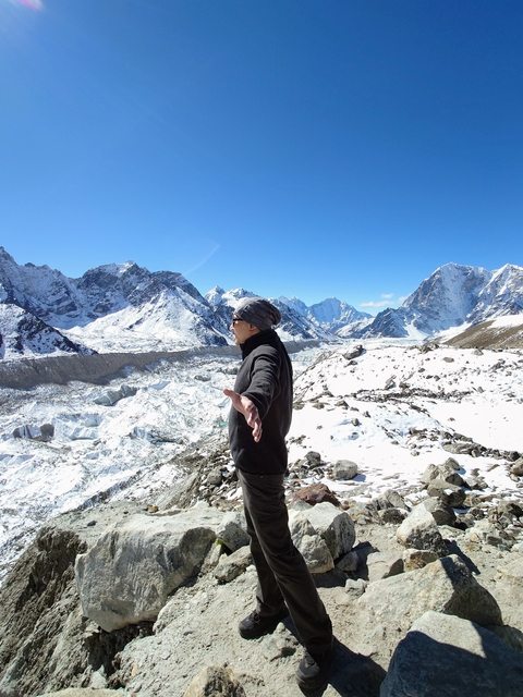 Person posing with arms outstretched on a snowy mountaintop.