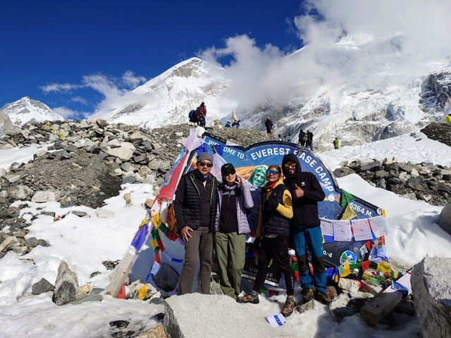 Group of people at Everest Base Camp with snowy mountains in the background.