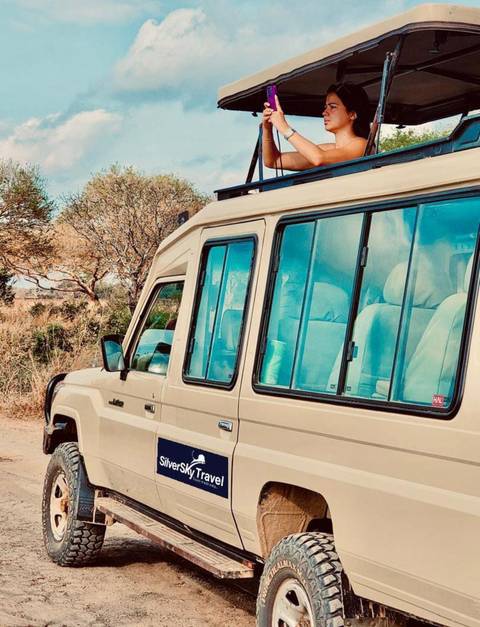Close-up of a safari vehicle parked on a dirt road.