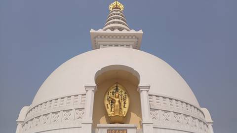 White Buddhist stupa with a golden statue.