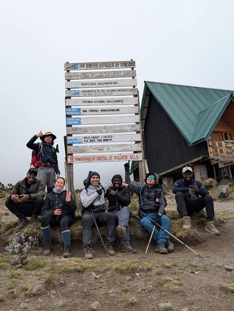 Group sitting by a sign at one of Tanzania's national park camps.