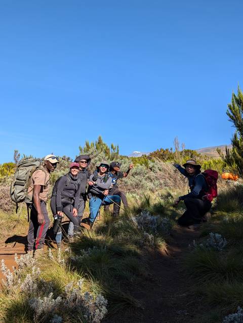 Hikers posing on a trail with surrounding vegetation and mountain view.
