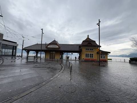 Vitznau railway station by a lake on a rainy day.