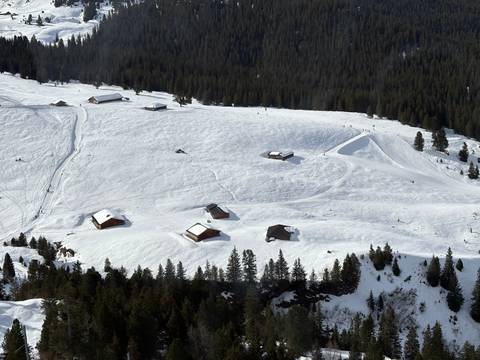 Aerial view of snowy hills and scattered small huts.
