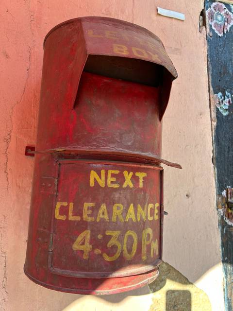 Close-up of a red postbox with yellow text.