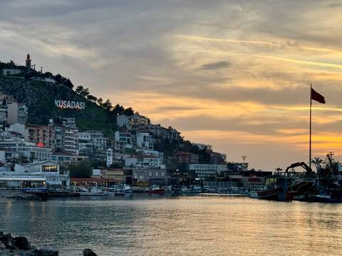 Coastal cityscape at sunset with Turkish flag.