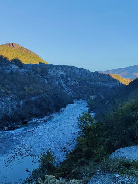A river flowing through a mountainous landscape at dusk.