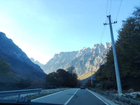A car driving on a road surrounded by majestic mountains.