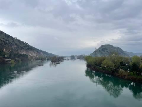 River view with mountains in the distance under cloudy sky.