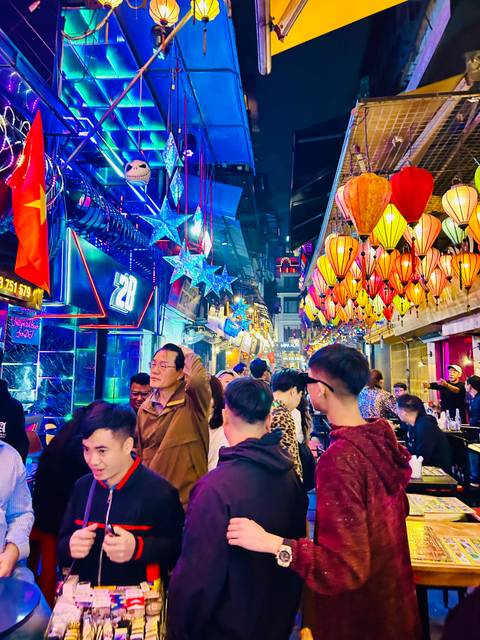 Crowded street market with vibrant lights and decorations.