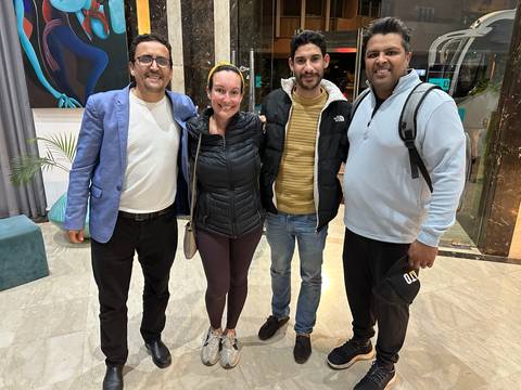 Group of people smiling and posing indoors in casual attire.