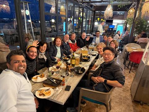 Large group dinner gathering with people smiling and waving.