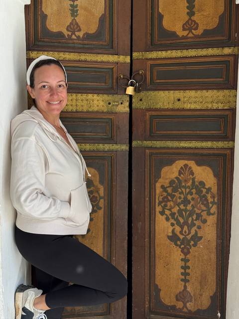 Person standing next to decorative wooden door.
