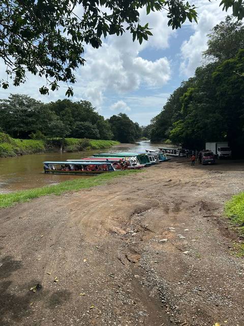 Boats lined up along a riverbank with people boarding.