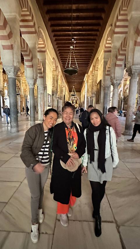 Three people inside a historical building with columns and arches.