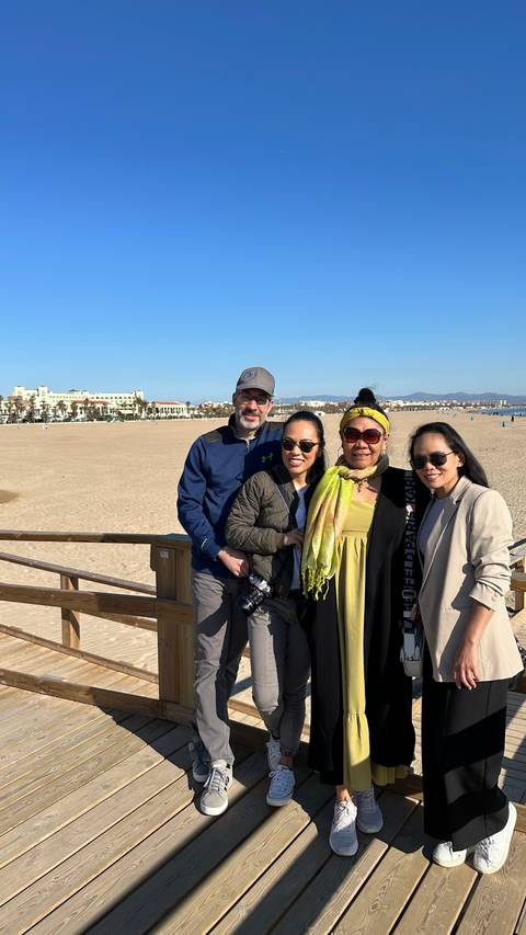 Group of people posing on a beach with a city in the background.