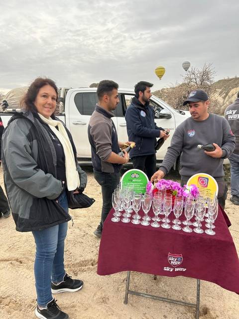 People pouring drinks outdoors near a vehicle.
