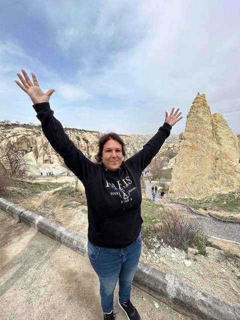 Person with arms raised in Cappadocia's landscape.
