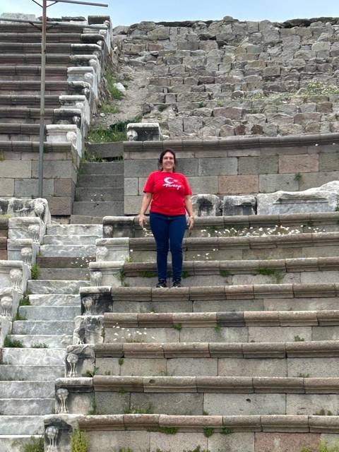 Person standing on ancient stone steps wearing a red Turkey shirt.