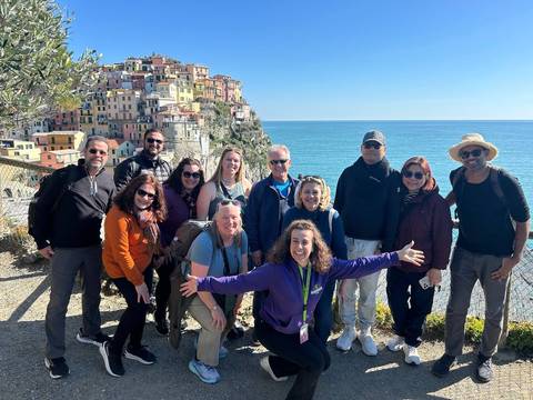 Group of people with a colorful cliffside town in the background, likely Cinque Terre.