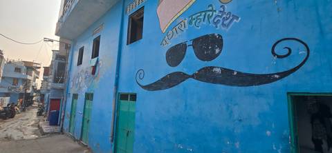 A blue-painted wall with a mural of sunglasses and a mustache.