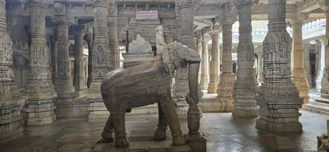 Interior of a temple with intricately carved stone pillars and an elephant statue.