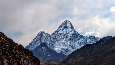 Majestic snow-capped mountain peak under overcast sky.