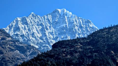 Bright sunlight illuminating a jagged, snowy mountain peak.