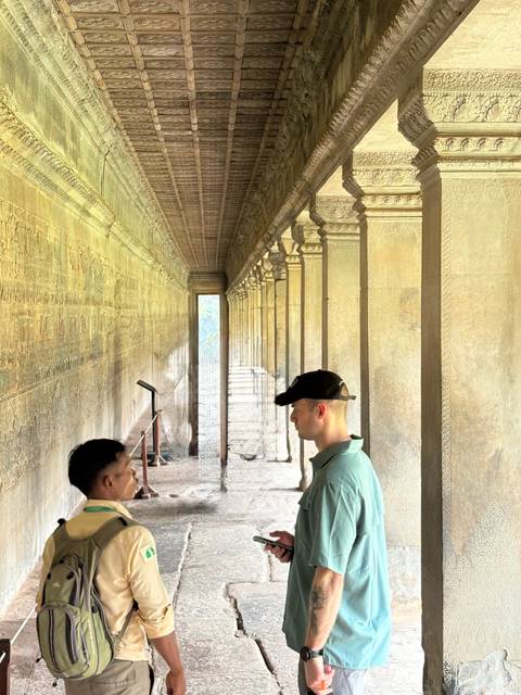 Two people talking in an ornate corridor.