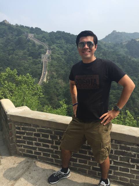 A man posing in front of the Great Wall of China.