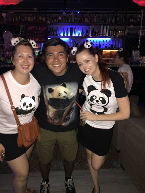 Three people posing with panda-themed shirts.