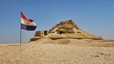 Ancient fortress with a flag under a blue sky.