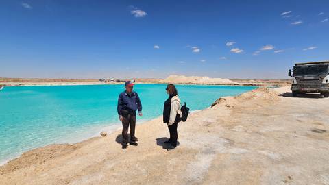 Two people standing by a vibrant blue lake.
