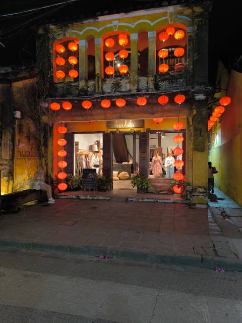 Street view of a shop illuminated by red lanterns at the entrance.