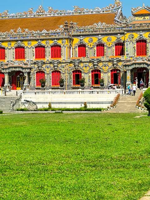 Grandiose structure with red windows and people milling about.