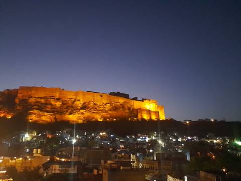 Night view of a fort lit by orange lights.