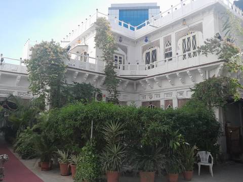 White building with lush greenery and ornate details.