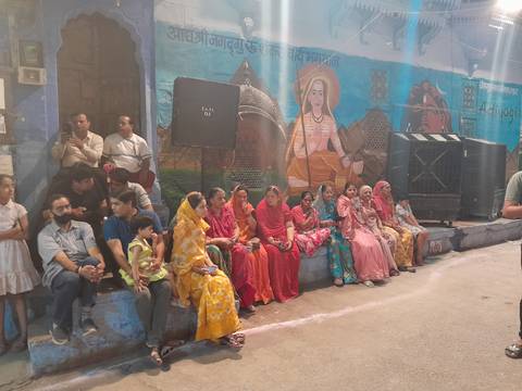 People seated near a street with colorful murals.