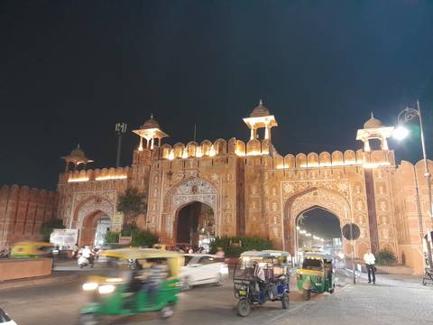 Illuminated city gate at night with traffic passing by.