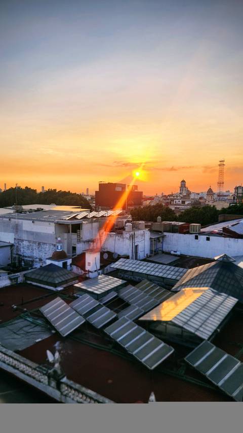 Sunset over city skyline with a prominent tower.