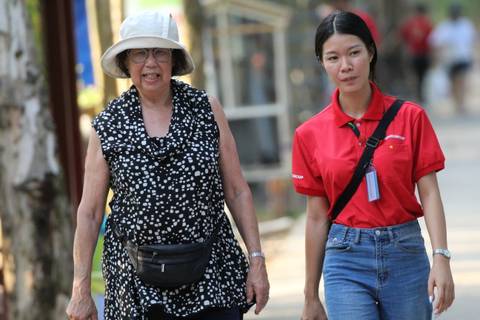 Two women walking, one in a red shirt and the other in a black dress.