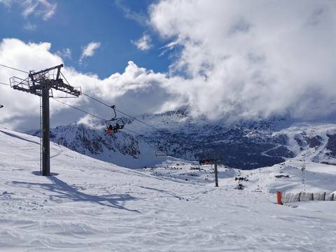 Snowy mountain ski area with ski lifts and cloudy skies.