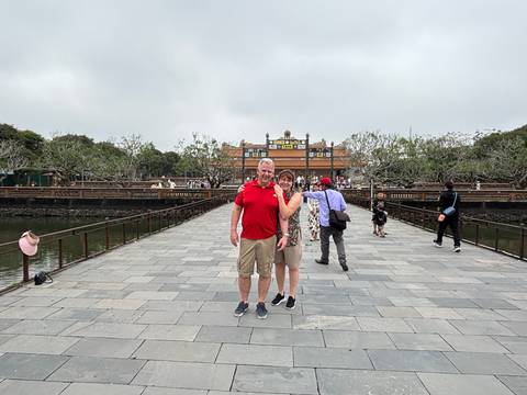Couple posing on a bridge in front of a historical building.