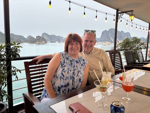 Couple seated by a waterway with limestone islands in the background.