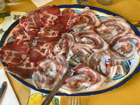 A plate of assorted Italian cured meats with a fork.