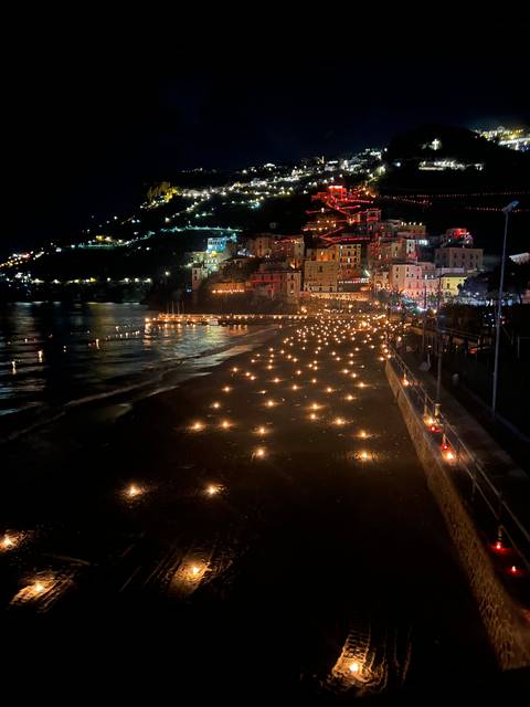 Night view of a coastal town with lights reflecting on the sea.