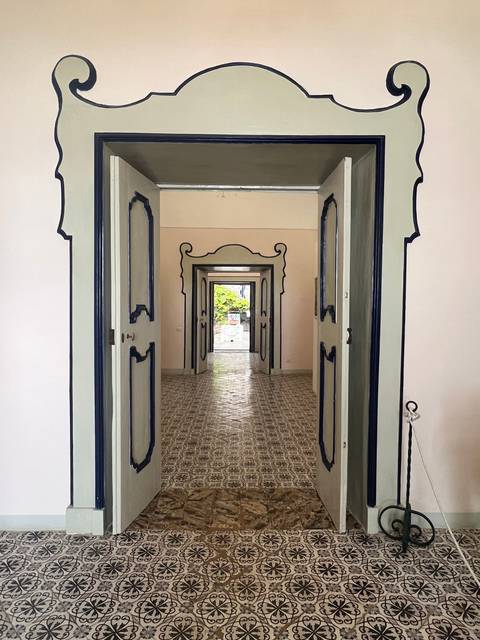A hallway with multiple door frames leading to an outdoor garden.