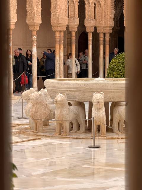 Lion fountain detail with a group of tourists observing.